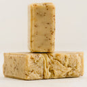 Two bars of beige soap with specks on a light beige background